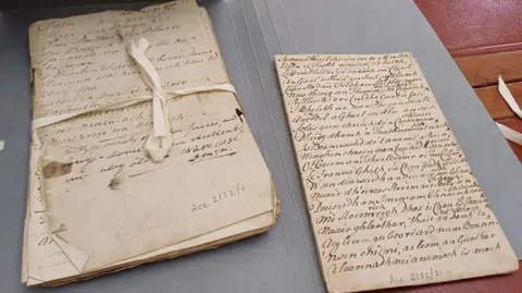 BBC The papers are bound with ribbon. Gaelic words have been handwritten in pen and ink across a page.