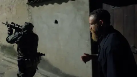 BBC/True North Ashley Cain in a favela with a man holding a large weapon