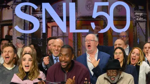 Getty Images SNL cast members under a large illuminated SNL50 sign