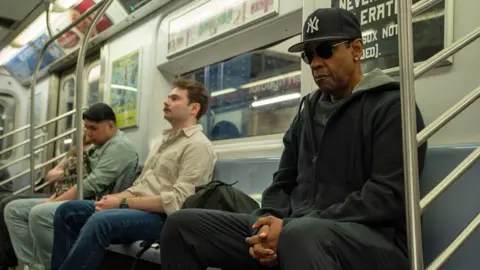 Escape Artists Denzel Washington in dark glasses and a baseball cap on the New York subway in a still from Highest 2 Lowest