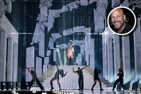 Getty Images Spanish singer Melody performs on top of a giant staircase at Eurovision 2025. Stage manager Richard van Rouwendaal is pictured in an inlay at the top right hand side of the image.