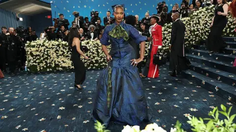 Getty Images Tems poses at the Met Gala, wearing a blue and green patterned dress