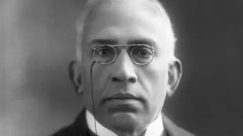 Alamy A black and white photo of C Sankaran Nair wearing a suit against a black background as he looks into the camera