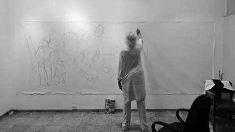 Pundole Art Gallery A man sketches on a huge canvas set in an art gallery