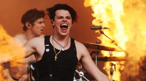 YungBlud performing on stage surrounded by jets of flame