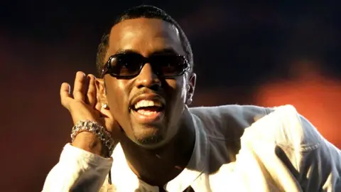 Reuters Diddy on stage smiling and with one hand cupped to his ear