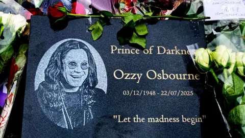 BBC A plaque with a picture of Ozzy and the words "Princde of Darkness Ozzy Osbourne 03/12/1948-22/07/2025 'Let the madness begin'"