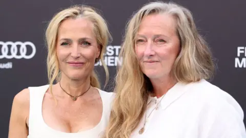 Getty Images Gillian Anderson and Raynor Winn attend the premiere of the movie The Salt Path during the 2025 Munich Film Festival on 1 July. They are both wearing white tops.