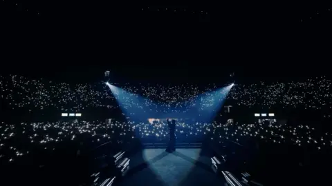 Himesh Reshammiya/Instagram Spotlights flash over Reshammiya as he sings in front of thousands of people gathered at a stadium in Delhi for his show 