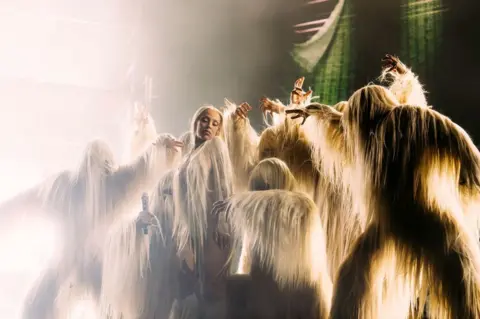 Greg Noire Doja Cat and dancers on stage in furry white costumes