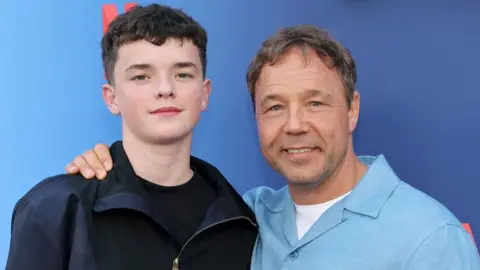 Getty Images Actor Stephen Graham, wearing a light blue shirt, puts his arm around fellow Adolescence star Owen Cooper at an event on May 27, 2025 in north Hollywood, California