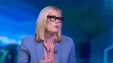 Getty Images Fiona Eastwood pictured in 2025. She is wearing a blue pastel coloured blazer, a salmon coloured blouse, and thick-rimmed dark glasses, and she has blonde shoulder length hair. She appears to be mid-talking during an on stage interview event 