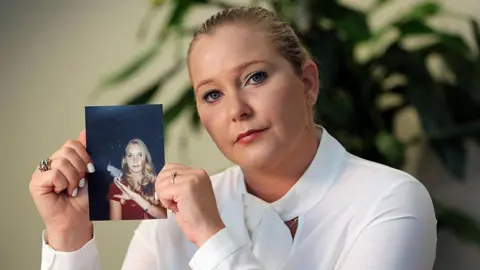 Getty Images Virginia Giuffre holding a picture of herself as a teenager