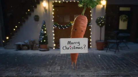 Aldi Kevin the Carrot is back holding a Marry Christmas sign