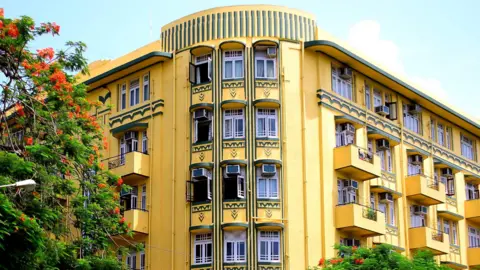 Art Deco Mumbai Trust The butter-yellow, bottle-green, dual-toned facade of the multi-storey Shiv Shanti Bhuvan building at Mumbai's Oval Maidan.