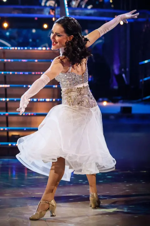 Amber dancing on her own in a white dress on the Strictly dance floor.