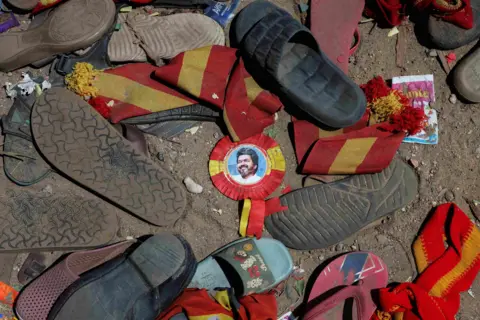Reuters A portrait of actor-turned-politician Vijay is seen near the scattered shoes after a stampede that broke out last evening during his political rally in the Karur district, in the Indian state of Tamil Nadu, on September 28, 2025.